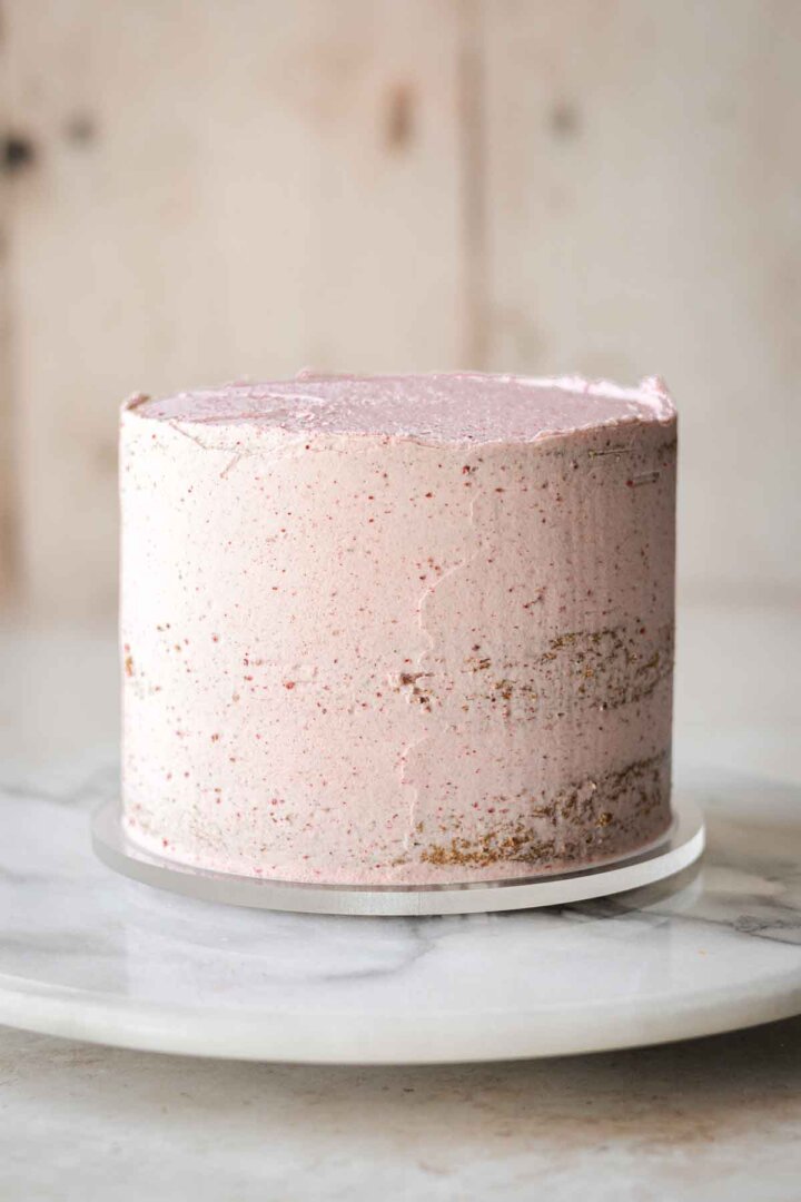 Matcha cake with a crumb coat of strawberry buttercream.