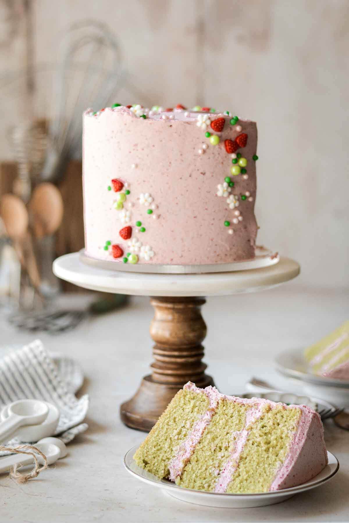 Pink and green strawberry matcha cake with a slice cut.