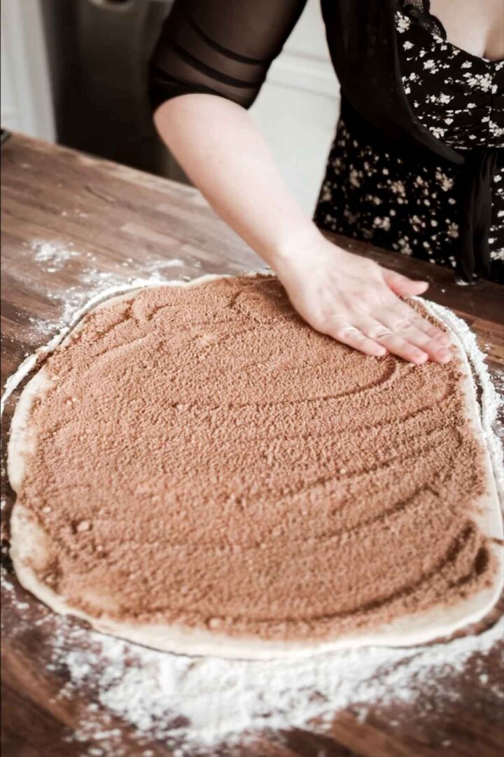 Step 2 for making a giant cinnamon roll cake - spreading cinnamon and sugar over the dough.