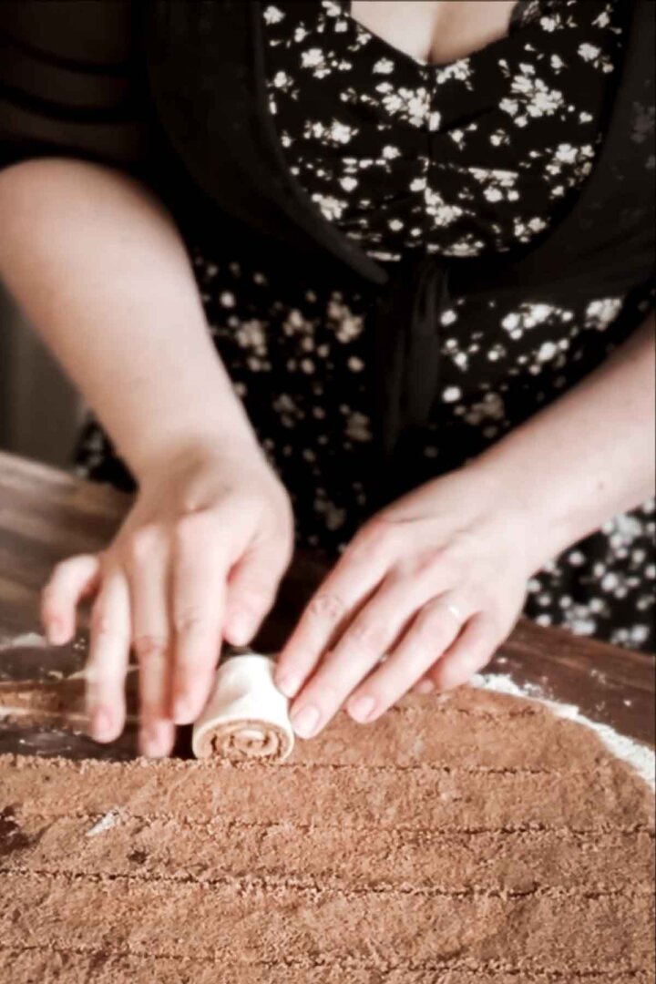 Step 3 for making a giant cinnamon roll cake - rolling up a strip of dough.