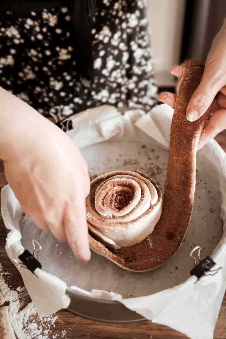 Step 5 for making a giant cinnamon roll cake - wrapping strips of dough in a spiral.