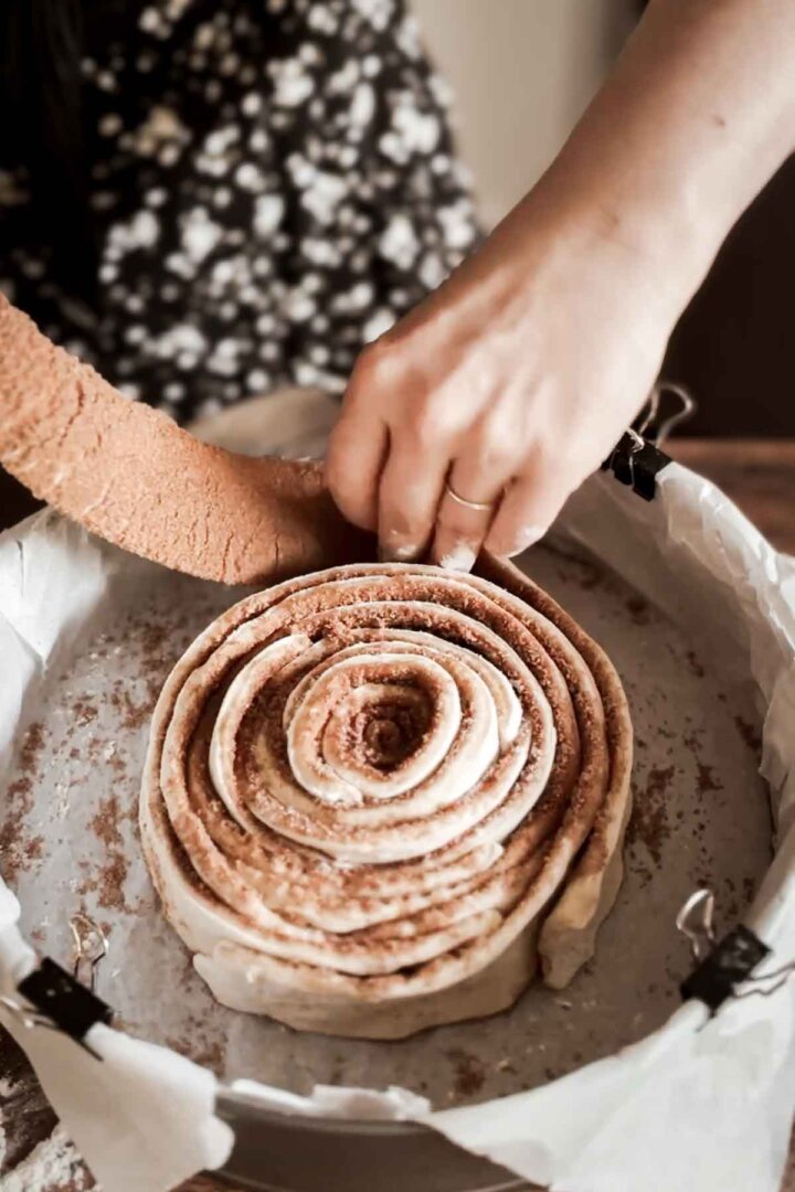 Step 6 for making a giant cinnamon roll cake - wrapping strips of dough in a spiral.