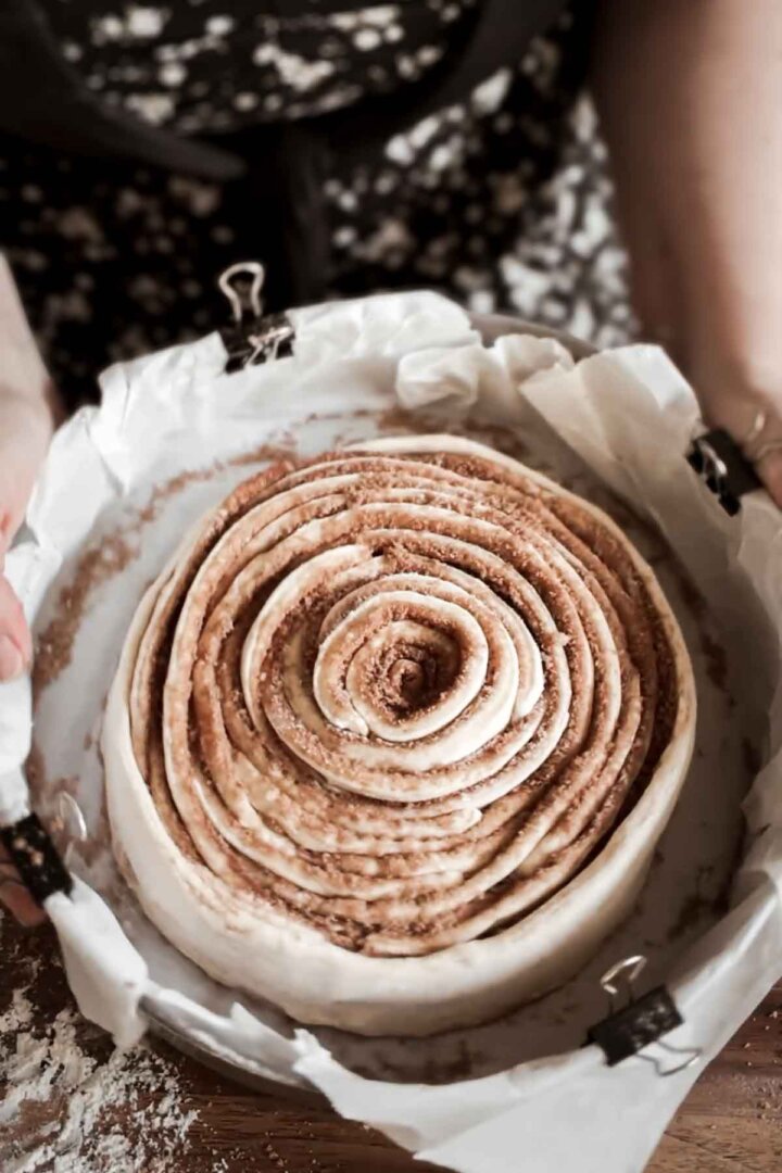 Step 7 for making a giant cinnamon roll cake - wrapping strips of dough in a spiral.