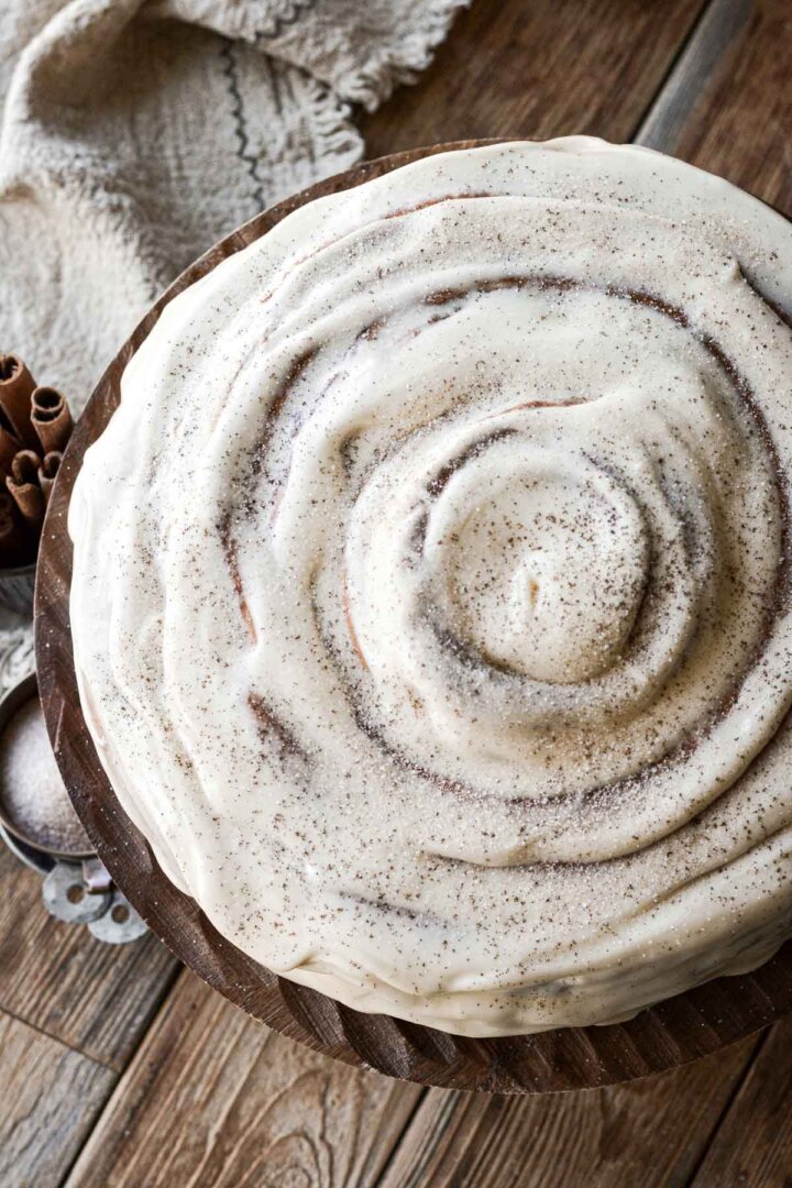 Cream cheese frosting spread onto a giant cinnamon roll.