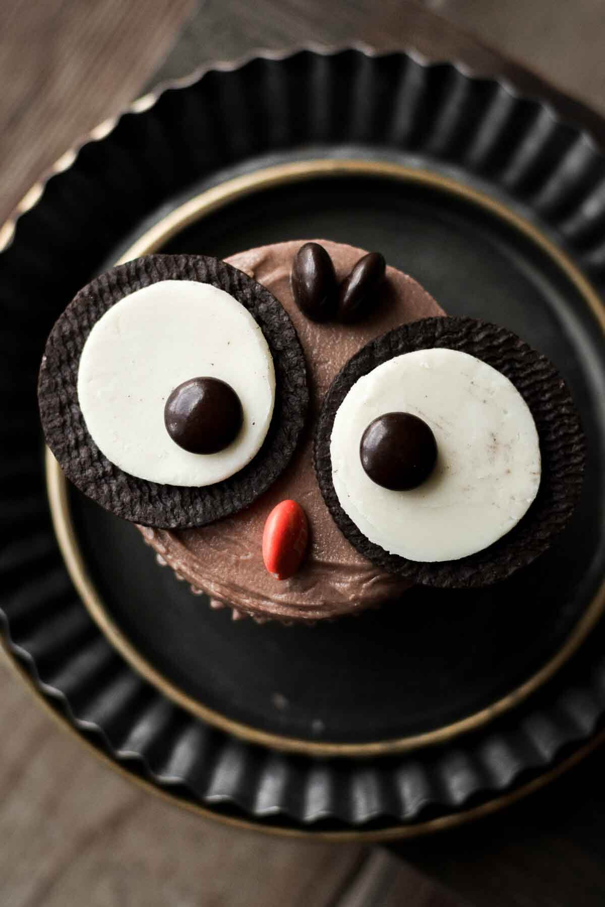 Owl cupcake decorated with Oreos and M&Ms.