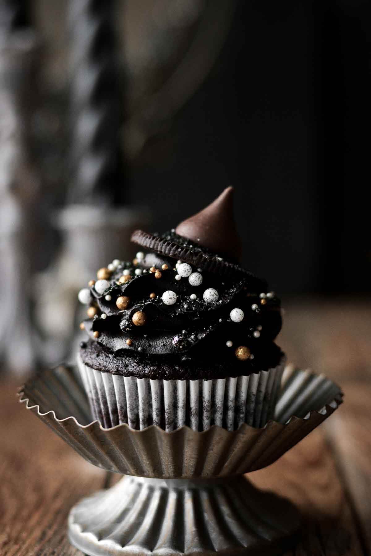Witch hat cupcake decorated with sprinkles, an Oreo, and a Hershey's kiss.