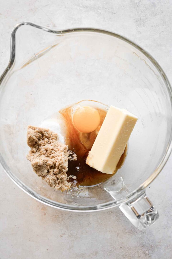 Step 1 for making chocolate chip cookies - butter, sugar and egg in a mixing bowl.