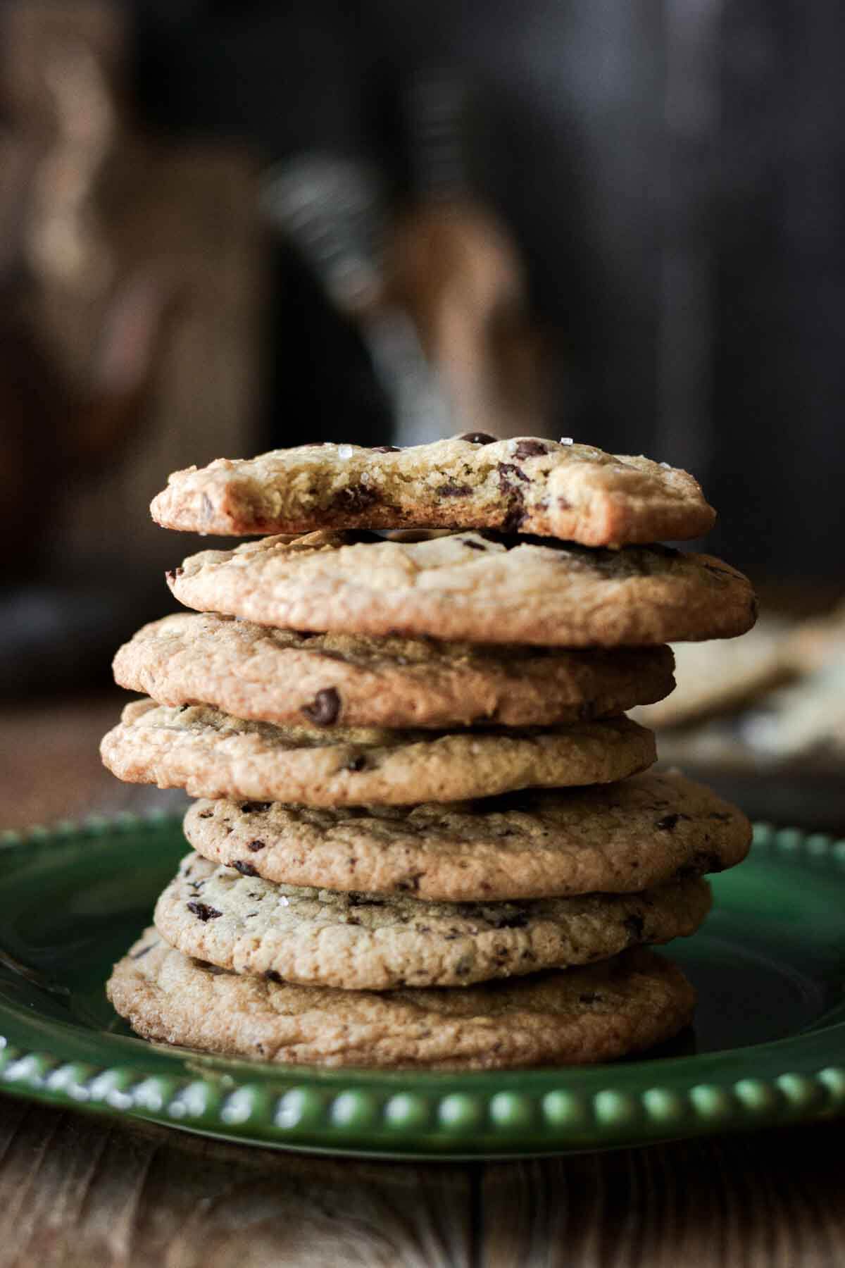 Stack of chocolate chip cookies, one with a bite taken.