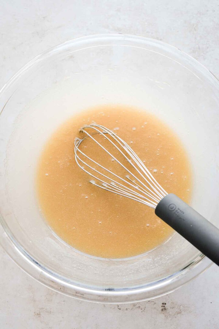 Step 1 for making chocolate chip cookies - whisking butter, sugar and egg.