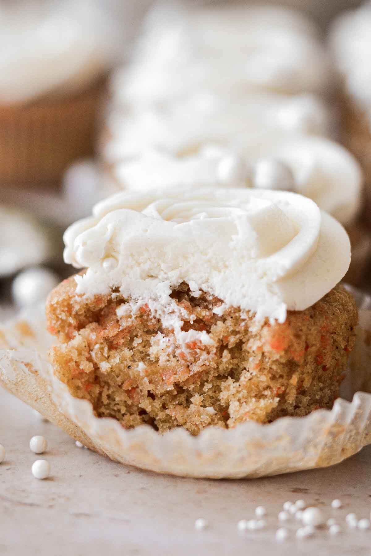 Carrot cake cupcake with a bite taken.