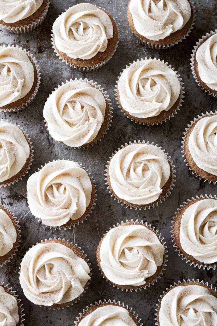 Carrot cupcakes frosted with piped rosettes of cream cheese frosting.