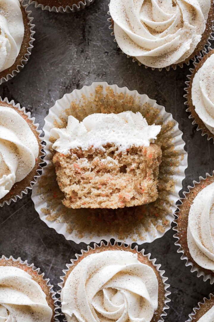 Carrot cake cupcake with a bite taken.