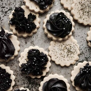 Gothic Halloween cookies with piped black cocoa buttercream on vanilla cutout cookies.