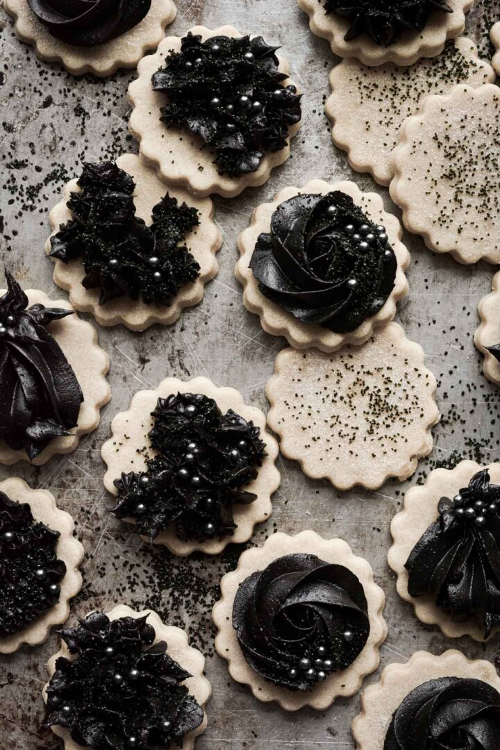 Gothic Halloween cookies with piped black cocoa buttercream on vanilla cutout cookies.