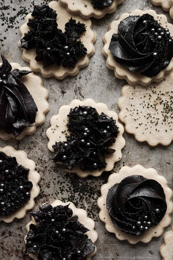 Gothic Halloween cookies with piped black cocoa buttercream on vanilla cutout cookies.