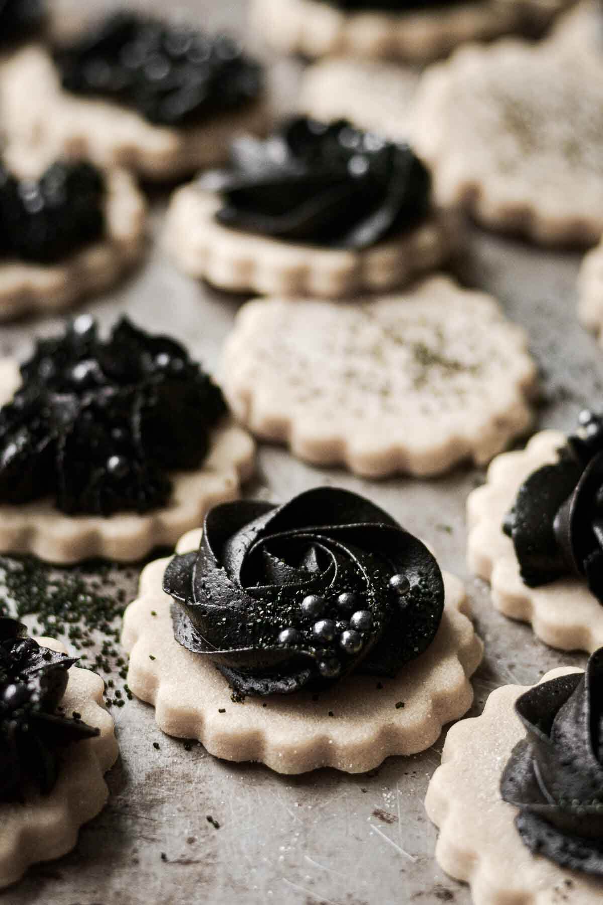 Gothic Halloween cookies with piped black cocoa buttercream on vanilla cutout cookies.