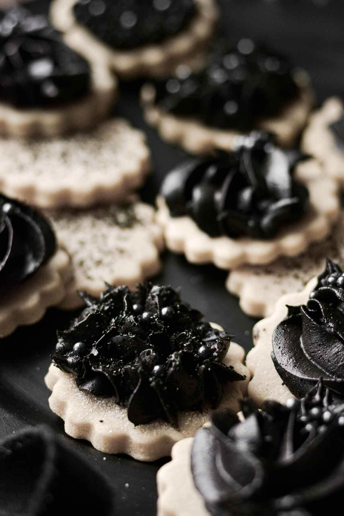 Gothic Halloween cookies with piped black cocoa buttercream on vanilla cutout cookies.
