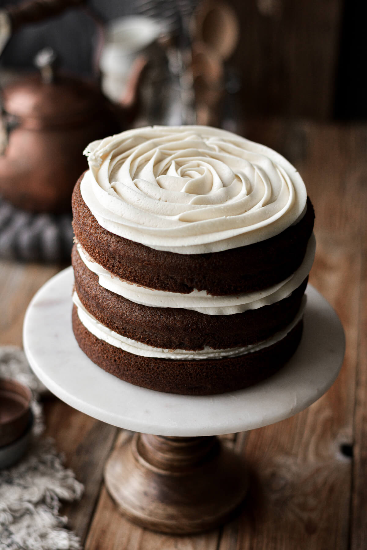 Piped cream cheese buttercream between layers of spice cake.