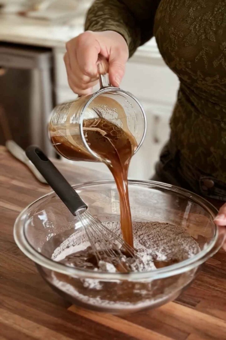 Pouring coffee into cake batter.