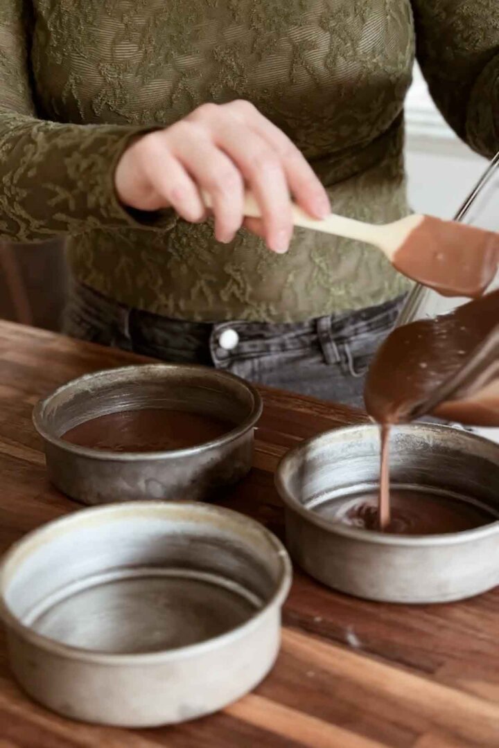 Pouring cake batter into pans.