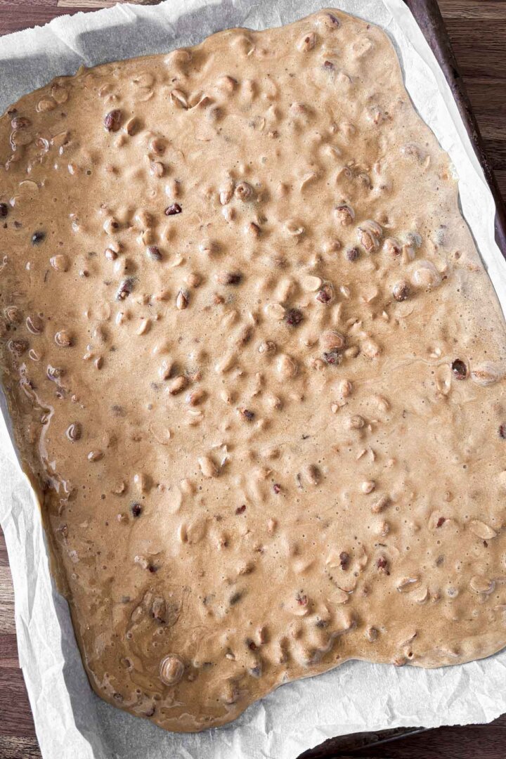 Step 5 for making peanut brittle - pouring the candy onto a baking sheet to harden.