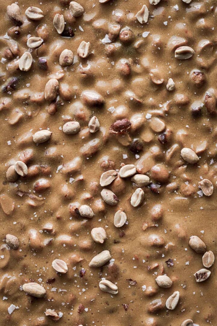 Step 6 for making peanut brittle - sprinkled with peanuts and flaky salt.