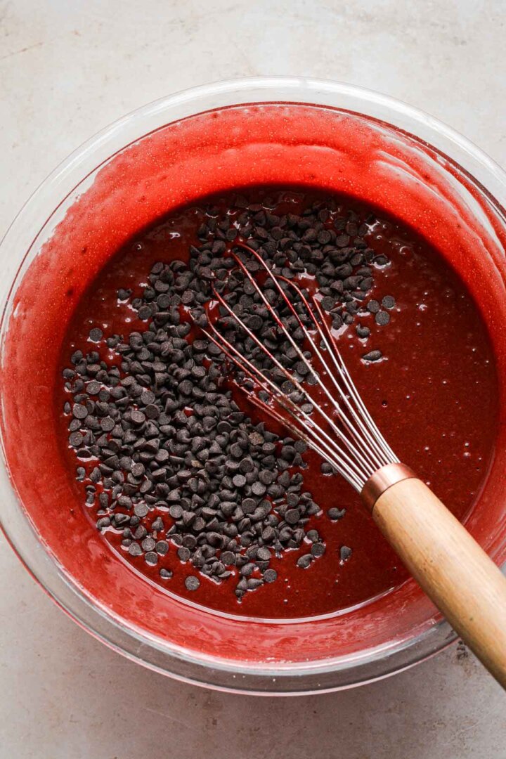 Step 3 for making red velvet chocolate chip cake - whisking in chocolate chips.