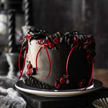 A gothic red velvet chocolate chip cake for Halloween, with black cocoa buttercream and red ribbons.