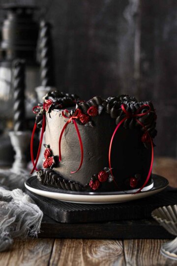 A gothic red velvet chocolate chip cake for Halloween, with black cocoa buttercream and red ribbons.