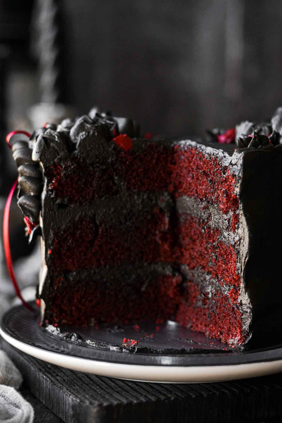 Red velvet chocolate chip cake with black buttercream, cut to show the inside layers.