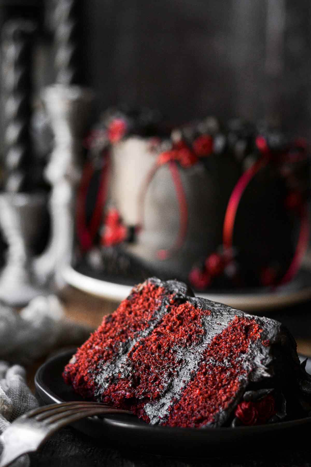 A slice of red velvet cake with black cocoa buttercream.