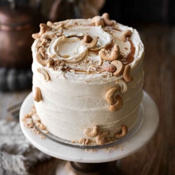 Salted caramel cashew cake, decorated with swirls of caramel and salted cashews.