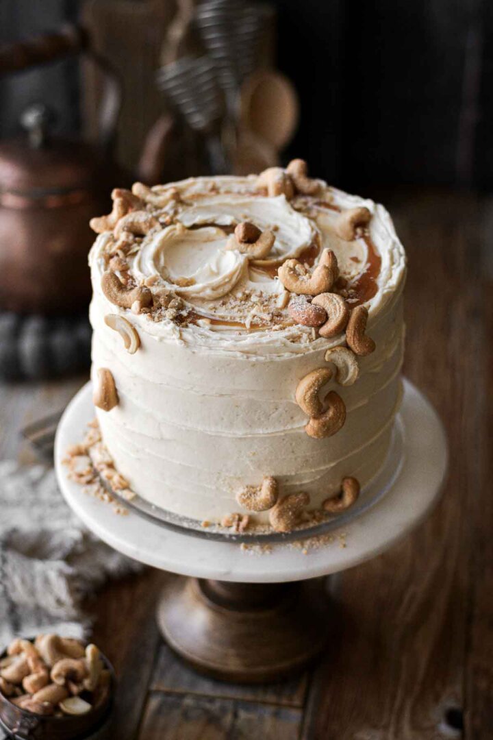 Salted caramel cashew cake, decorated with swirls of caramel and salted cashews.