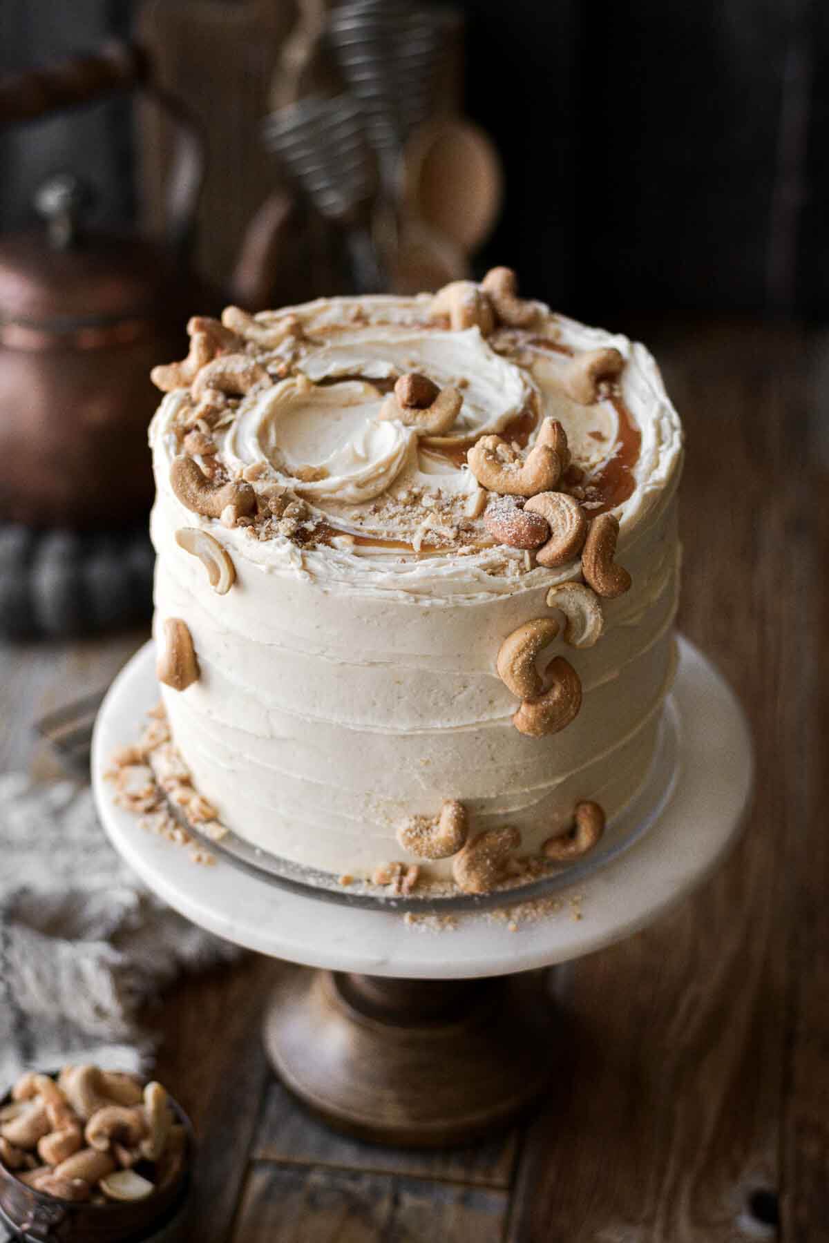 Salted caramel cashew cake, decorated with swirls of caramel and salted cashews.