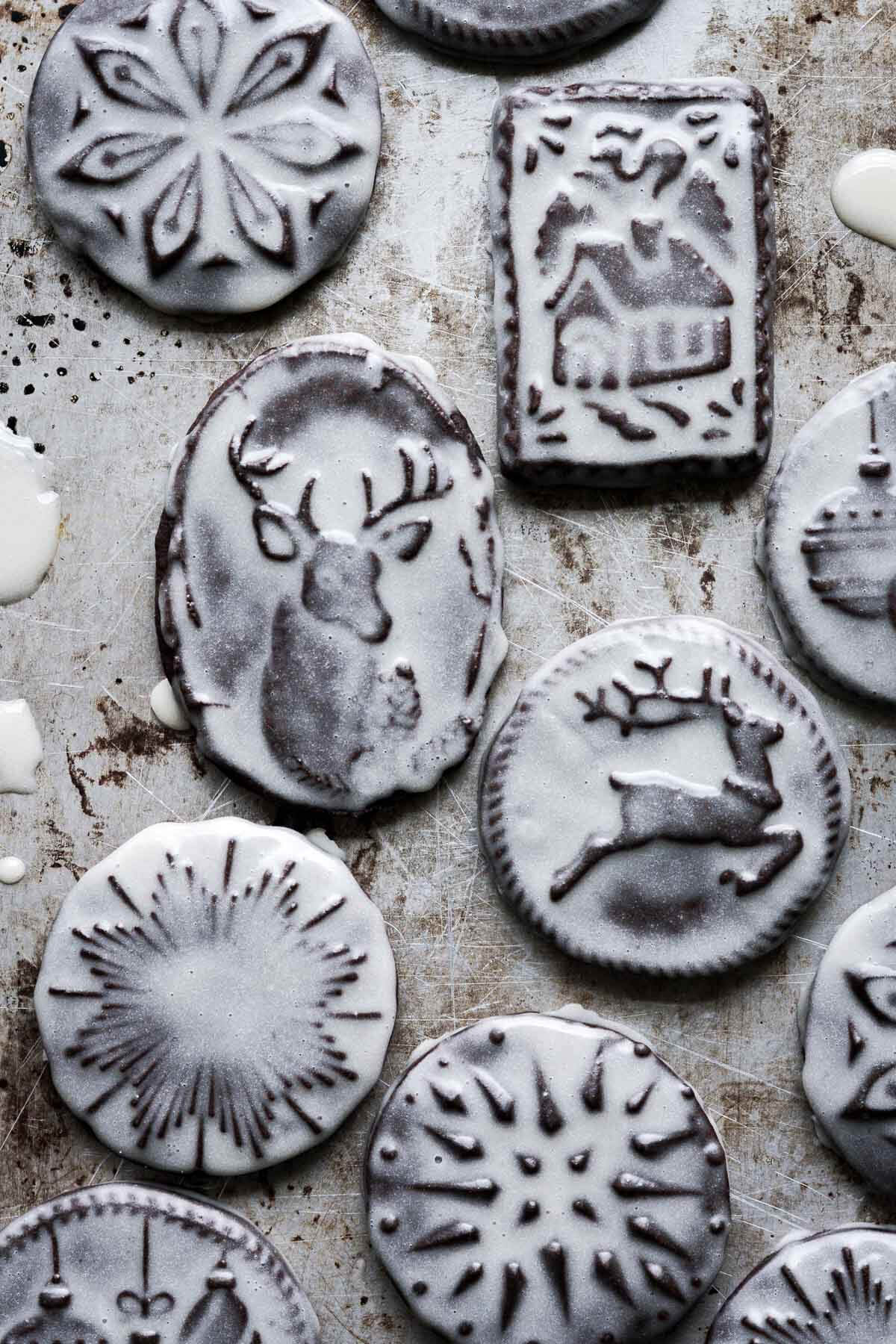 Iced chocolate Christmas cookies stamped with Christmas designs.