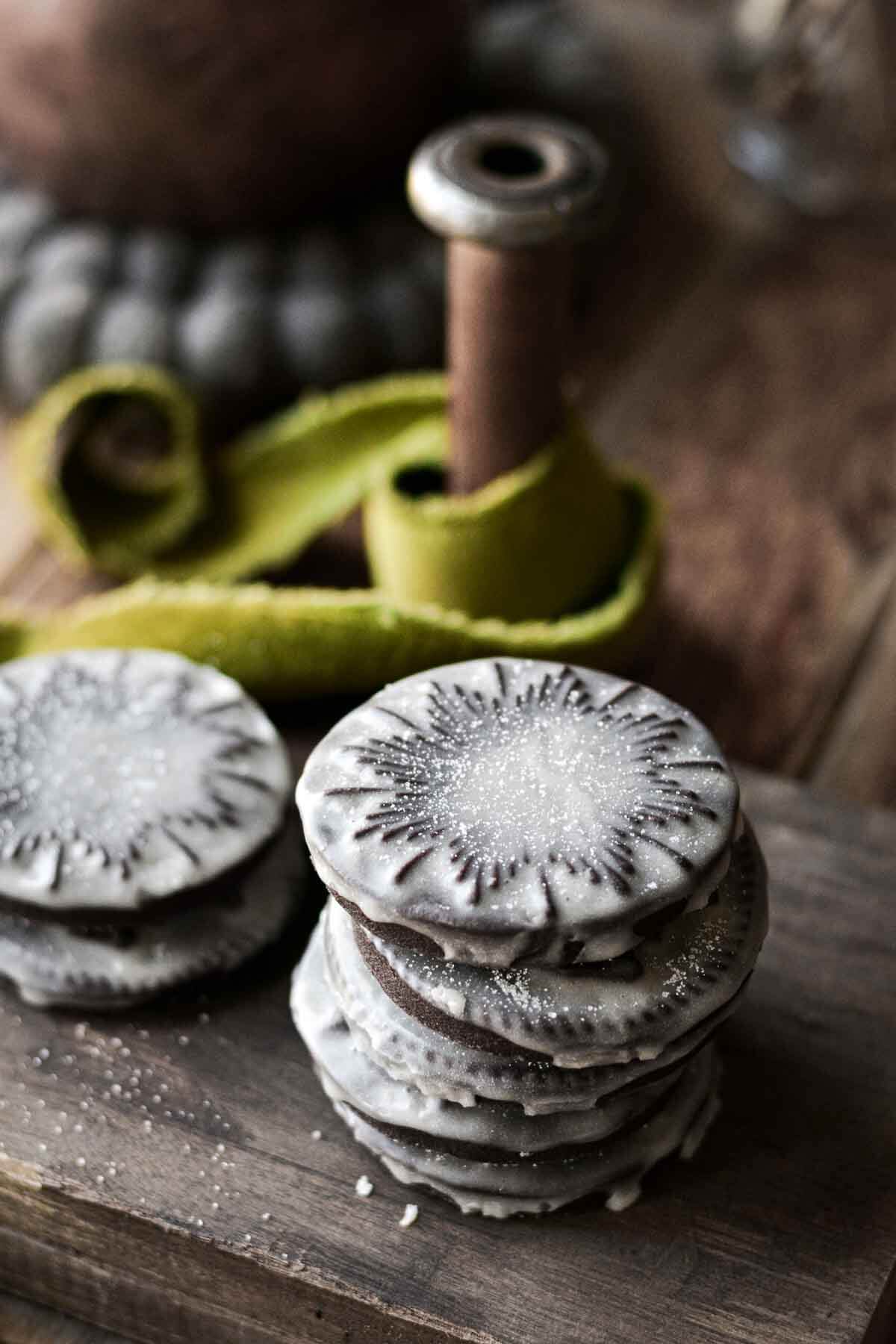 Stack of iced stamped chocolate cookies on a wooden board.